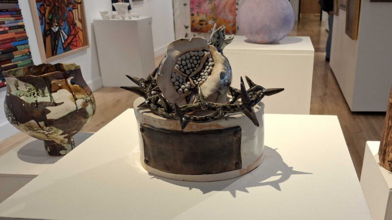 A sculpture of a pomegranate surrounded by thorns that relates to the story of Eve and women's choices.